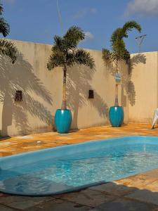 deux vases bleus avec des palmiers devant une piscine dans l'établissement Palmeira’s du Vento, à Cruz