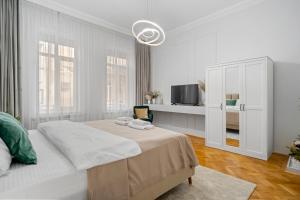 a white bedroom with a bed and a tv at Central Luxury Apartments with Private Garden & Parking in Bucharest