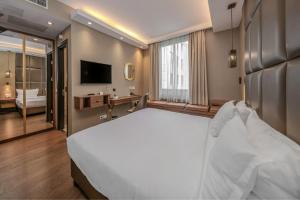 a bedroom with a large white bed and a television at Continental Hotel Budapest in Budapest