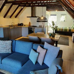a living room with a blue couch and a kitchen at Appartement Badnieuweschans in Bad-Nieuweschans