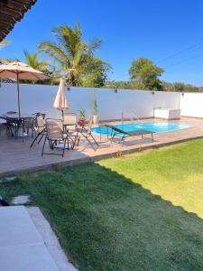een terras met een tafel en stoelen en een zwembad bij Praia Grande House in Fundão