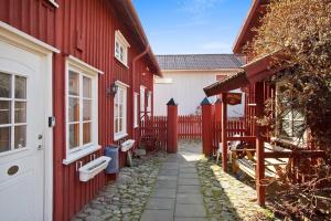 um caminho entre dois edifícios vermelhos com uma cerca em Hotell Mikaelsgården em Vargarda