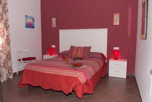 a bedroom with a bed with red walls and two lamps at Viviendas Turísticas El Mero in Zahora