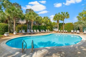 a swimming pool with chairs and palm trees at 30A - Cassine Station by Panhandle Getaways in Santa Rosa Beach