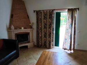 a living room with a fireplace and a couch and a window at Albufeira INN - Mulatinho V3 in Olhos de Água