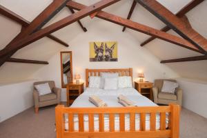 a bedroom with a wooden bed and two chairs at Award Winning Lower Whitsleigh Farm Cottage in Roborough