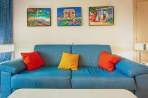 a blue couch with colorful pillows in a living room at Sublime Stay - Royal Retreats at Maho Beach in Lowlands