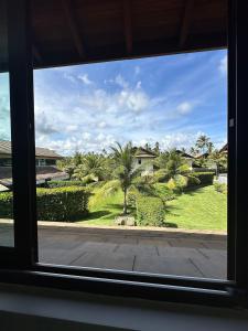 a window view of a yard with palm trees at House 16 - Reserva dos Carneiros in Tamandaré