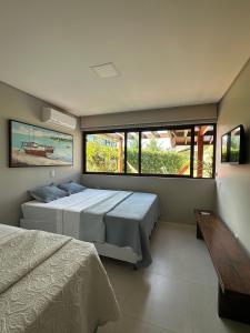 a bedroom with two beds and a large window at House 16 - Reserva dos Carneiros in Tamandaré