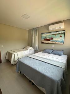 two beds in a hotel room with a painting on the wall at House 16 - Reserva dos Carneiros in Tamandaré +32 photos