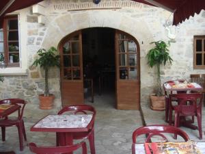 um restaurante com mesas e cadeiras e um edifício de pedra em Hotel Des Arts em Puybrun