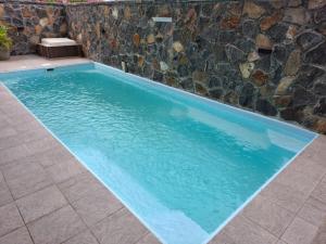 Azur Horizon Residence في فليك-إن-فلاك: مسبح بمياه زرقاء وجدار حجري