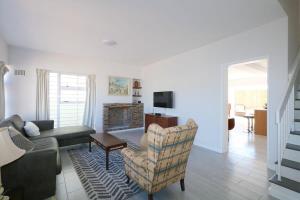 una sala de estar con un sofá y una silla en Royal House, en Muizenberg