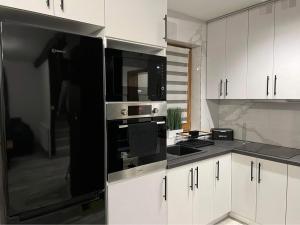 a kitchen with white cabinets and black appliances at Domek 11 osobowy in Jaworzynka