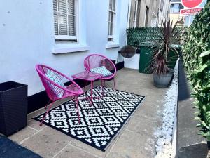 two pink chairs sitting on a rug next to a building at Aquila House in Saint Helier Jersey