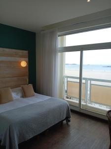 a bedroom with a bed and a large window at Alba hotel in Saint Malo