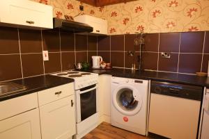 a kitchen with a washing machine and a washer at Bellbridge Cottage in Milltown Malbay