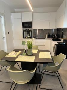 une cuisine avec une table et des chaises et une cuisine avec des armoires blanches dans l'établissement Studio apartman Mango, à Jadranovo