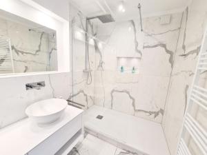 ein weißes Badezimmer mit Waschbecken und Dusche in der Unterkunft Ferienwohnung Lieblingssuite am Strand in Ahlbeck + 19 Fotos