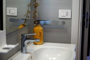 Un lavabo de baño con un espejo y un jarrón amarillo. en La perla del mare, en Mascali 7 fotos más