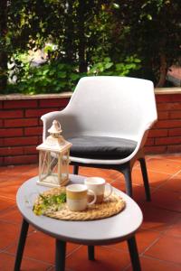 una silla y una mesa con tazas y una linterna en La perla del mare, en Mascali