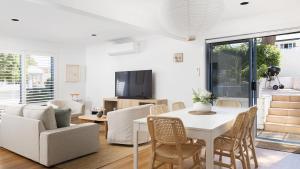 Una sala de estar con una mesa y sillas blancas. en Coastal Hideaway - Water Views and Walk To The Beach, en Corlette