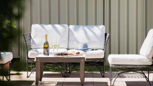 una silla y una mesa con una botella de vino y copas en Coastal Hideaway - Water Views and Walk To The Beach, en Corlette