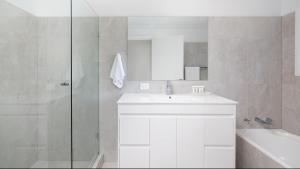 Un baño blanco con lavabo y ducha. en Coastal Hideaway - Water Views and Walk To The Beach, en Corlette 27 fotos más
