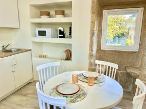 a kitchen with a white table and chairs and a window at O lar do magnolio in Pontevedra