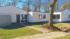 a white house with a tree in a yard at Bungalowpark Simpelveld - Schakel 15 in Simpelveld