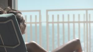 a woman sitting in a chair looking out a window at Hotel Delle Nazioni in Lido di Jesolo +59 photos