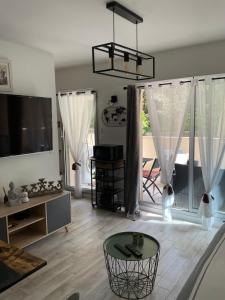 a living room with a table and a large window at Studio coin nuit terrasse parking Clim in Nice