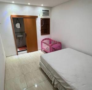 een slaapkamer met een wit bed en een roze stoel bij Praia Grande House in Fundão +21 foto's