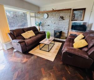 a living room with a leather couch and a fireplace at Bryn Gwyn Lodge in Newport