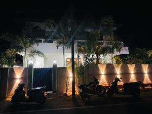 two motorcycles parked next to a fence at night at Kanapathiy Rest House in Trincomalee