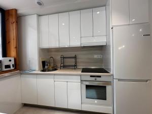 una cucina con mobili bianchi e un frigorifero in acciaio inossidabile di Loft in Bidezabal a Getxo