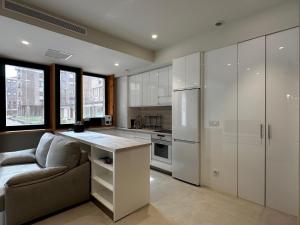 una cucina con armadi bianchi, divano e frigorifero di Loft in Bidezabal a Getxo Altre 4 foto