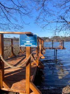 a sign on a wooden dock next to a body of water at Chatka nad jeziorem in Wólka