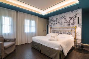 a bedroom with a large white bed and a chair at Terme Preistoriche Resort & Spa in Montegrotto Terme +145 photos