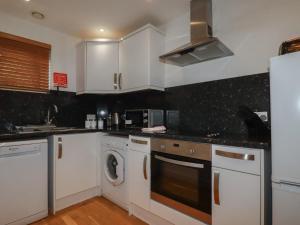 a kitchen with white cabinets and a washer and dryer at Tregullan in Truro +10 photos