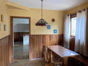 a dining room with a wooden table and a light at Banyvas Chalés in Monte Verde