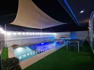 a swimming pool at night with a table and chairs at Sea Life Poolville in Jomtien Beach