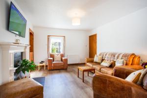 a living room with a couch and a tv at Mike's 3-bedroom Countryside Cottage in Alness
