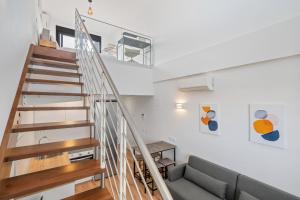 a living room with a staircase and a couch at atico duplex con piscina y parking incluido ALQUILER TEMPORAL in San Sebastián de los Reyes +35 photos