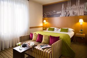 
a hotel room with a bed, table, lamp and a painting on the at Starhotels Tourist in Milan
