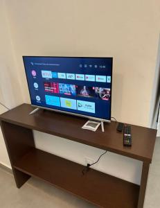 a television on a wooden stand with a remote control at 13 Studio completo, perto TRT, Smartfit, Life Center, cozinha in Belo Horizonte
