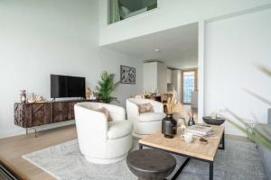 a living room with two white chairs and a table at 3 Bedroom Luxury Waterside House in Hayle