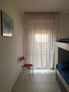 a bedroom with a red chair and a window at Luminoso Appartamento al mare in Martinsicuro