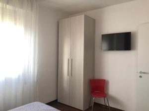 a bedroom with a cabinet and a red chair at Luminoso Appartamento al mare in Martinsicuro