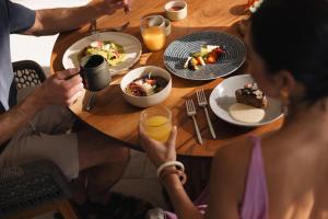 a group of people sitting around a table with food at Almare, a Luxury Collection Resort, Isla Mujeres Cancun, Adult All-Inclusive in Isla Mujeres
